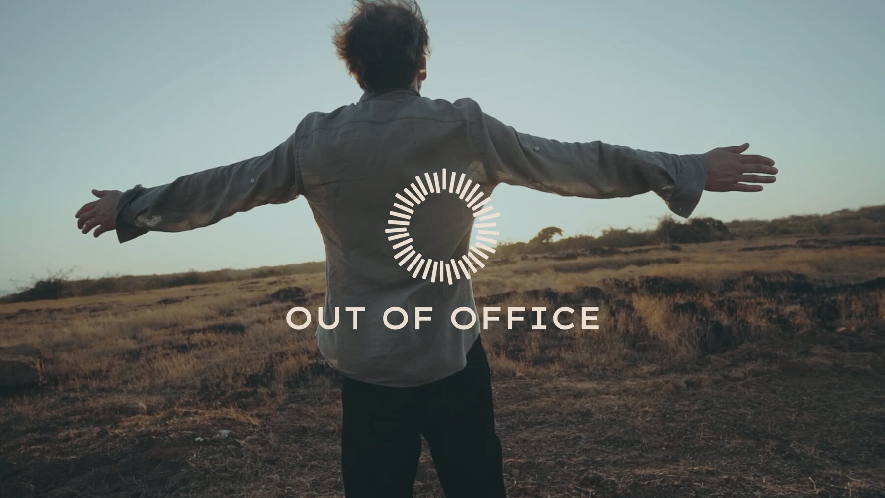 Out of Office logo, arms open in a field